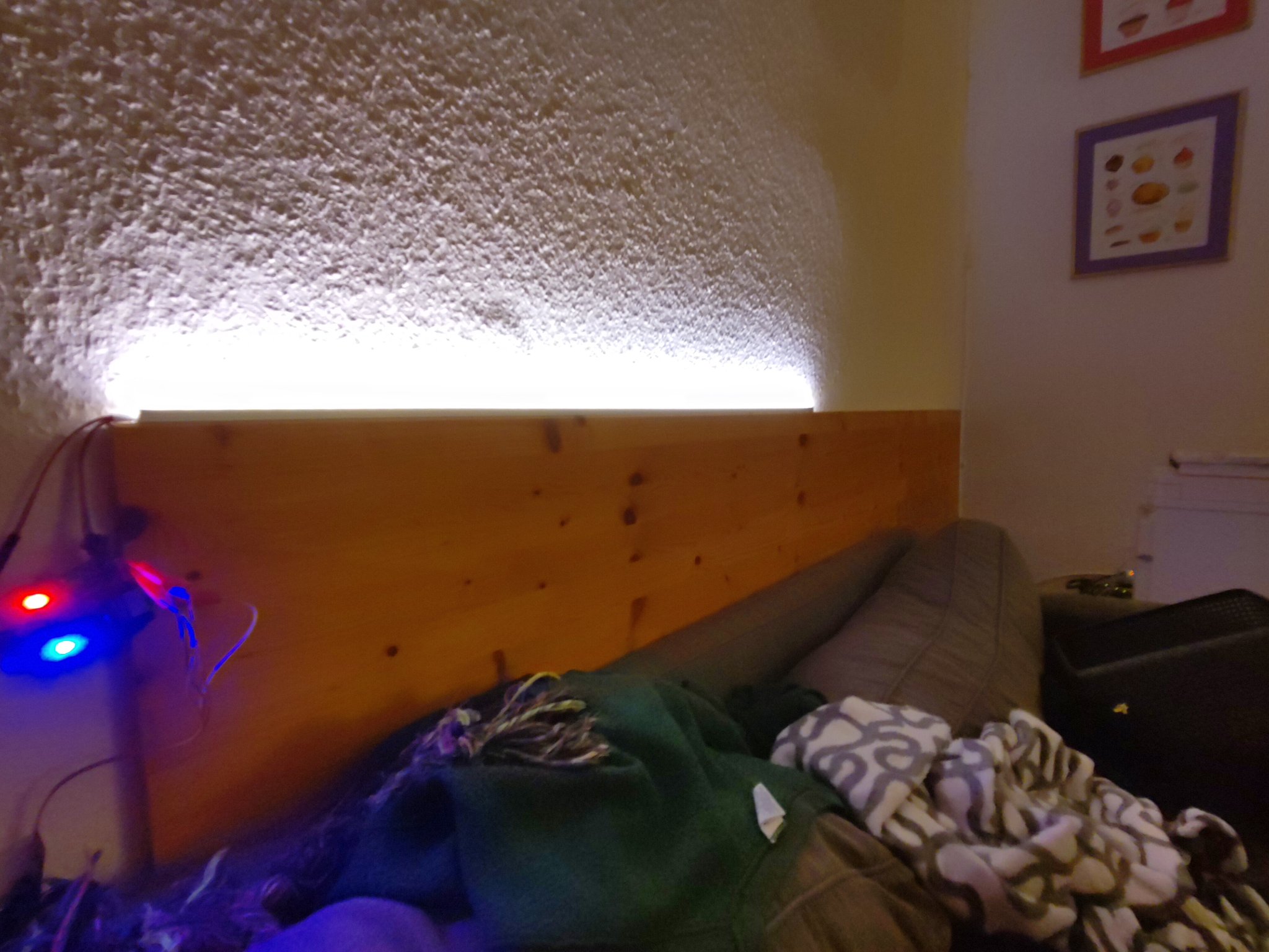 An LED bar mounted behind a couch, shining a bar of warm white light upwards